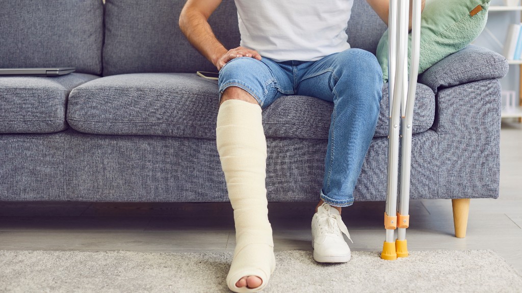 A man with a broken leg sits on the sofa in the living room
