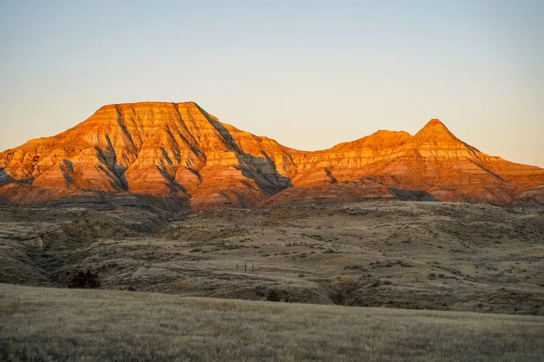 Sunlit rugged mountains with layered rock formations under a clear sky.